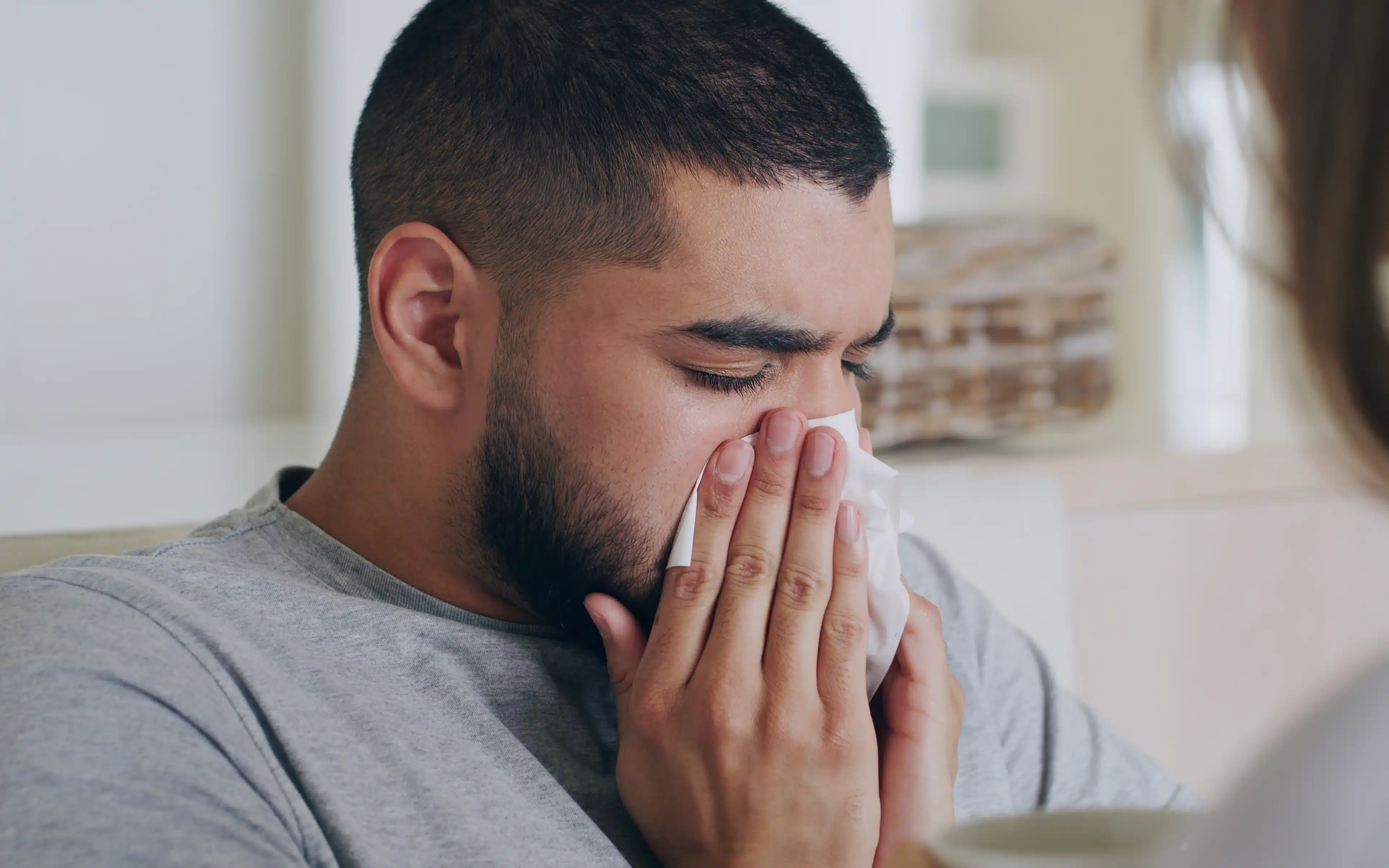 A male, perhaps on a cruise ship, sneezing with cold or flu symptoms.
