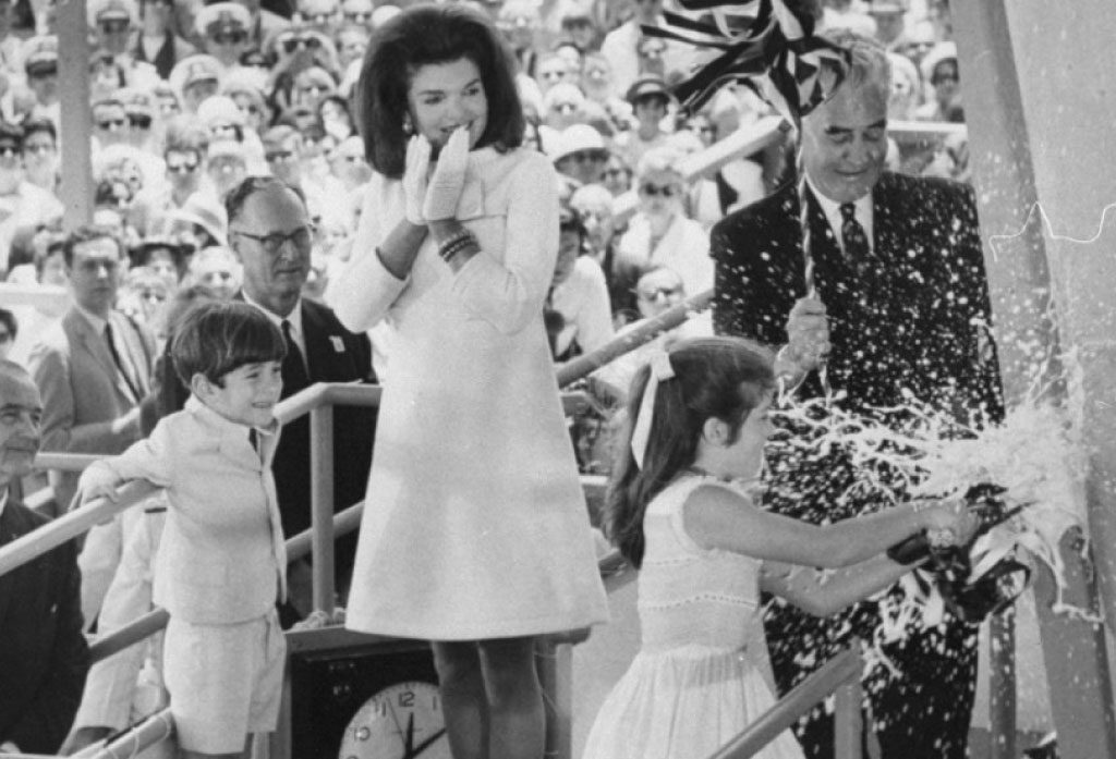 Carol Kennedy christens the USS John F. Kennedy as Jackie Kennedy watches on.