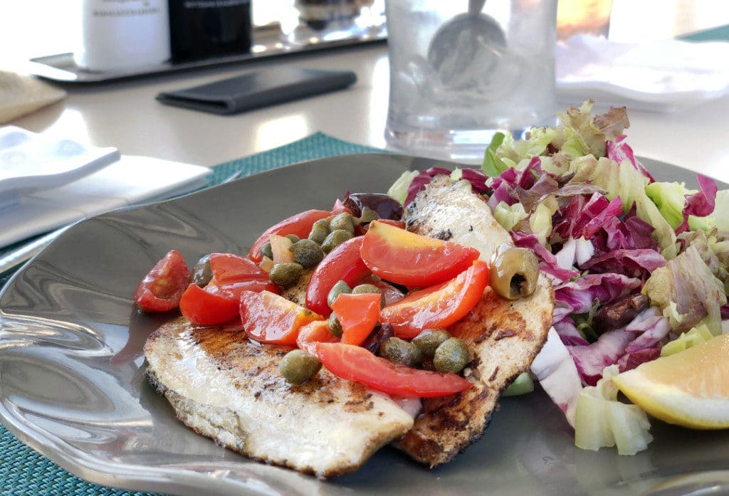 The fish of the day is grilled and served with tomatoes, capers and lemon.