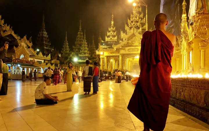 A Buddhist monk in reflection at Shwedagon Pagoda in Myanmar.