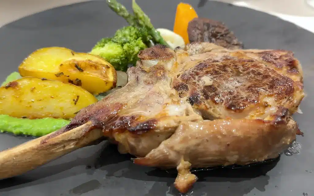 A veal chop with vegetables.