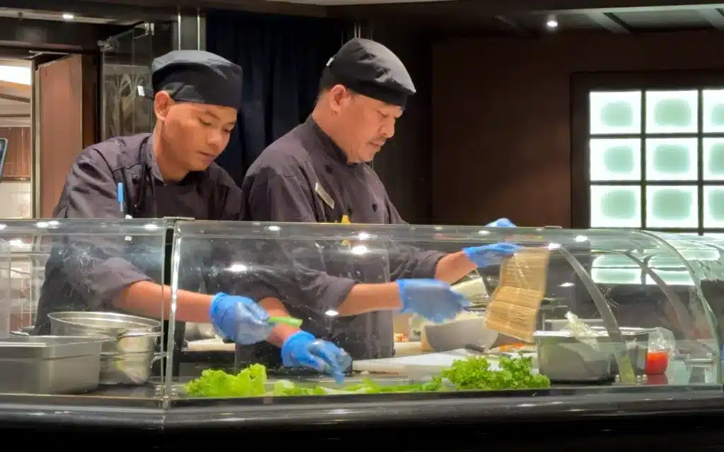Two sushi chefs behind a sashimi bar.