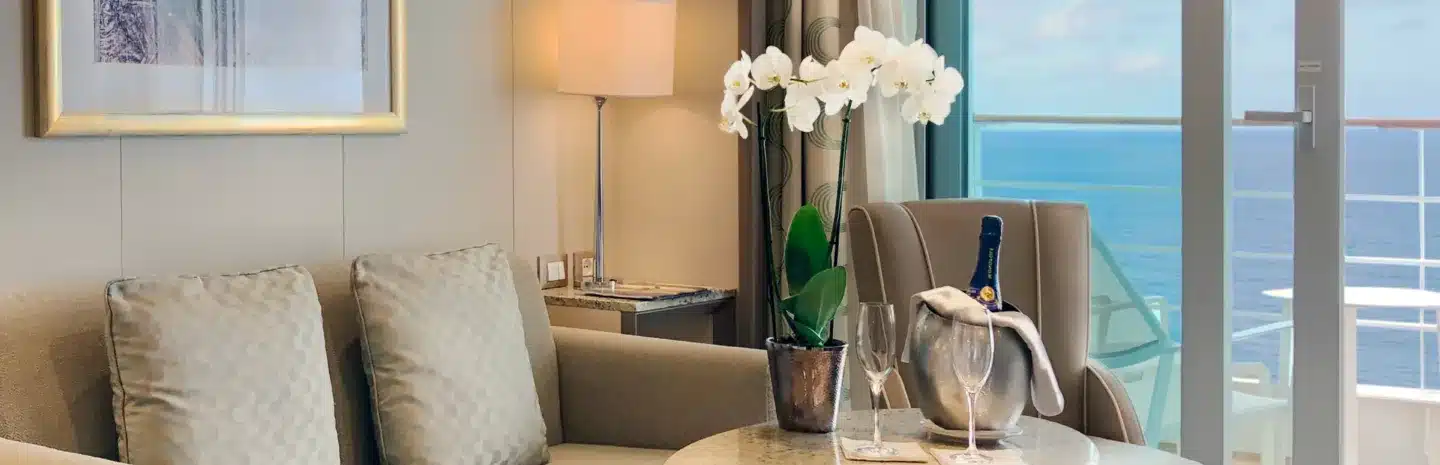 silver-muse-veranda-suite Champagne and an orchid rest on a coffee table with a view to the ocean behind.