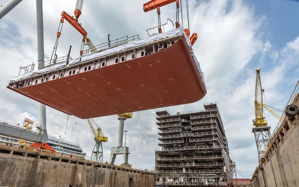 The first keel section of Seven Seas Grandeur is lifted into place.