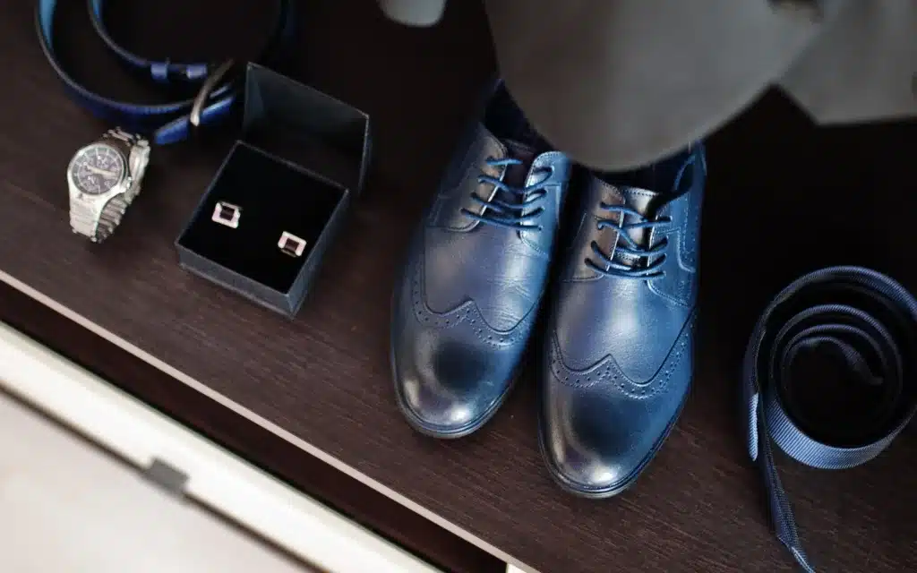 Close up of a men's dark suit, blue shoes and fashion accessories.