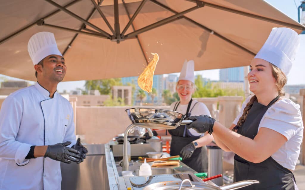 A chef teaches two females how to cook a new dish.