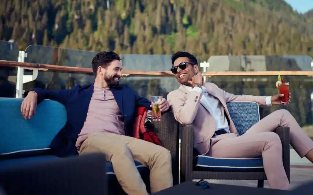 A male couple on deck with cocktails in Alaska.