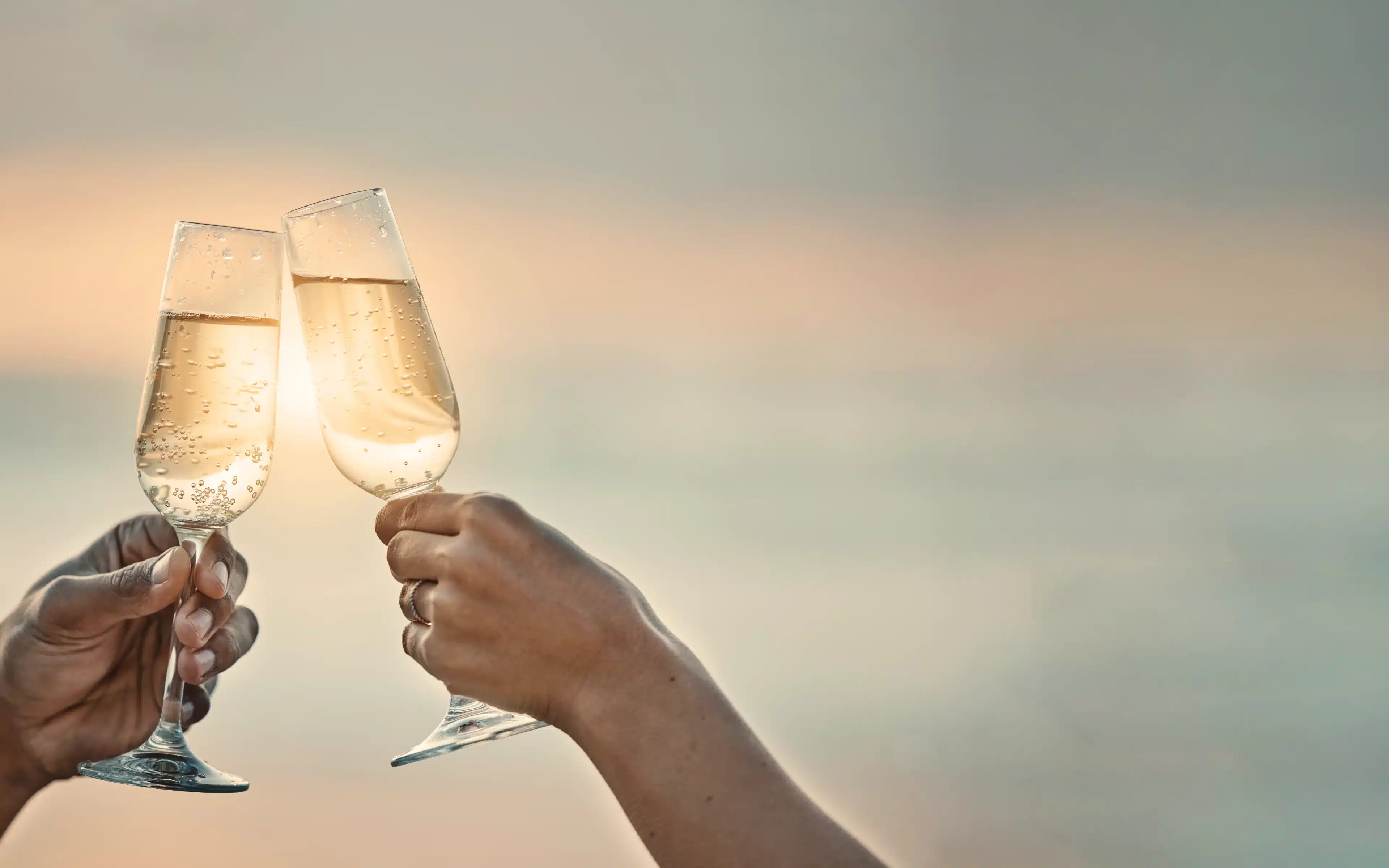 Sunset, a couple toast with wine glasses. A mofit for the luxury of Silversea vs Regent Seven Seas Cruises.