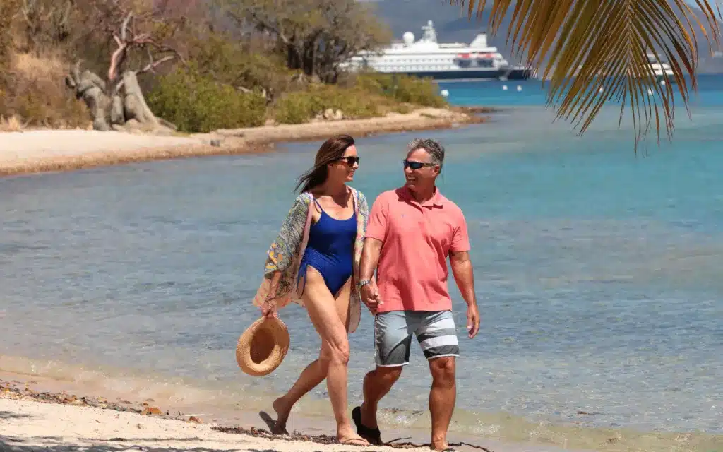 Couple walking on the beach with SeaDream II in the background in Norman Island.