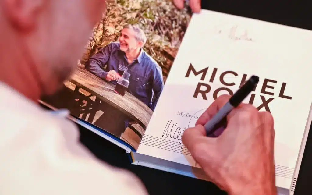 Michel Roux signing a cook book.