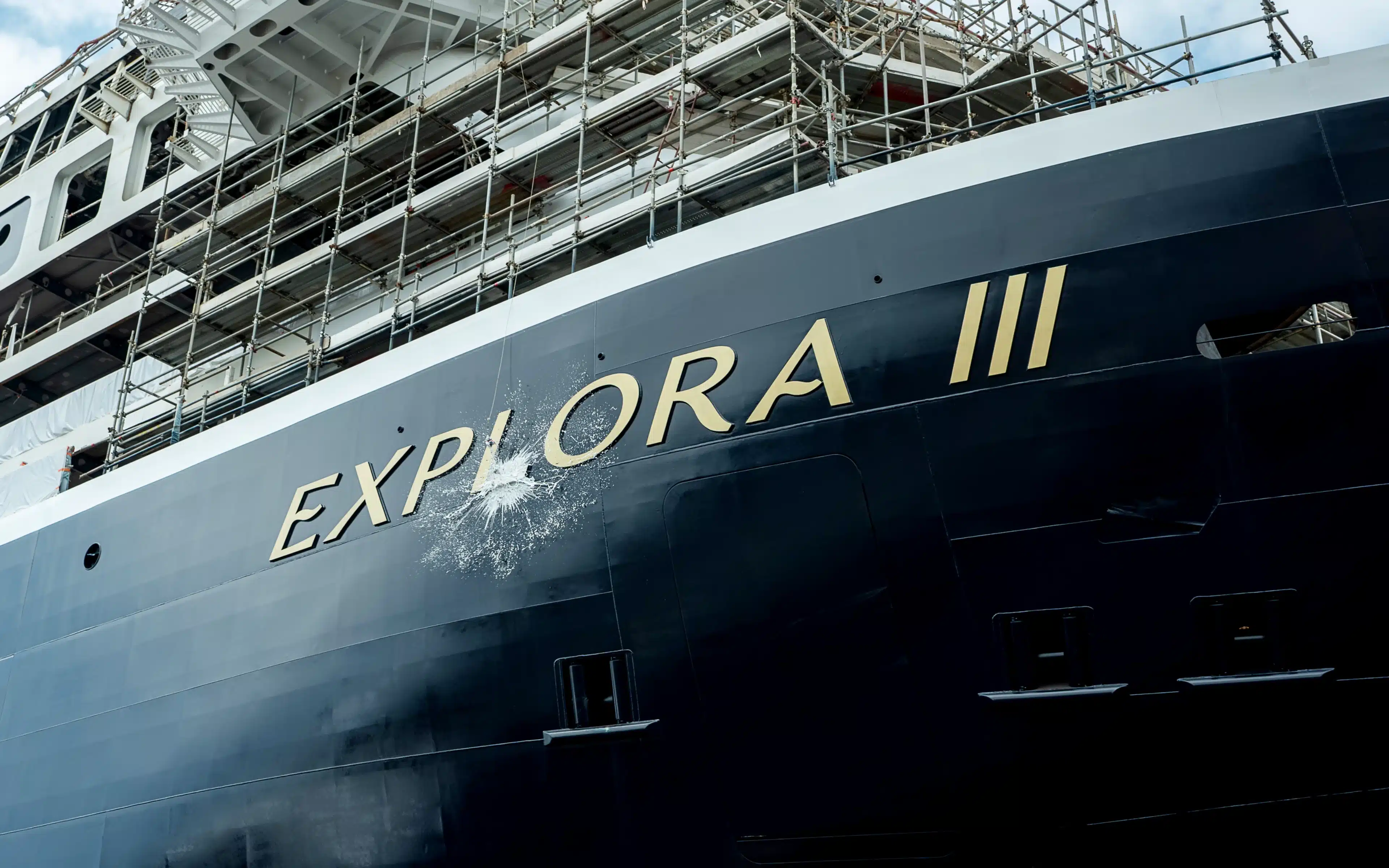 Champagne breaks over the bow of the Explora III cruise ship.