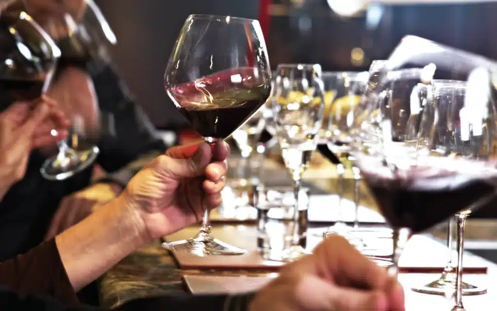 Hands hold up glasses of red wine.