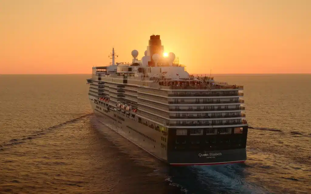 The Queen Elizabeth cruise ship sailing against a sunset.
