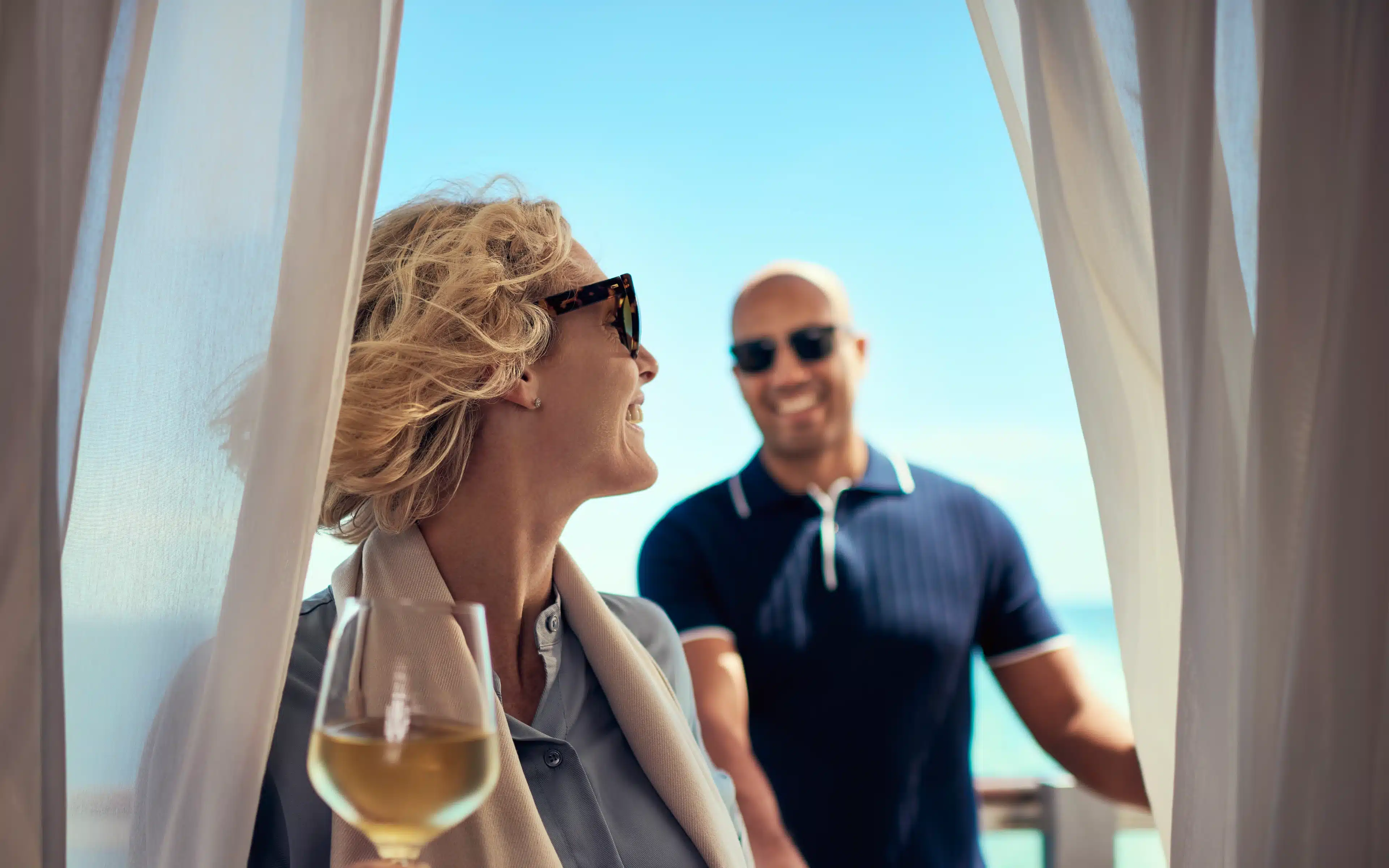 A man and female laughing together on a cruise ship balcony.