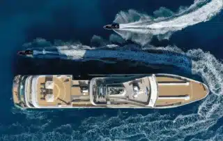 Viewed from above, an Aqua Expeditions vessel is circled by two Zodiacs.