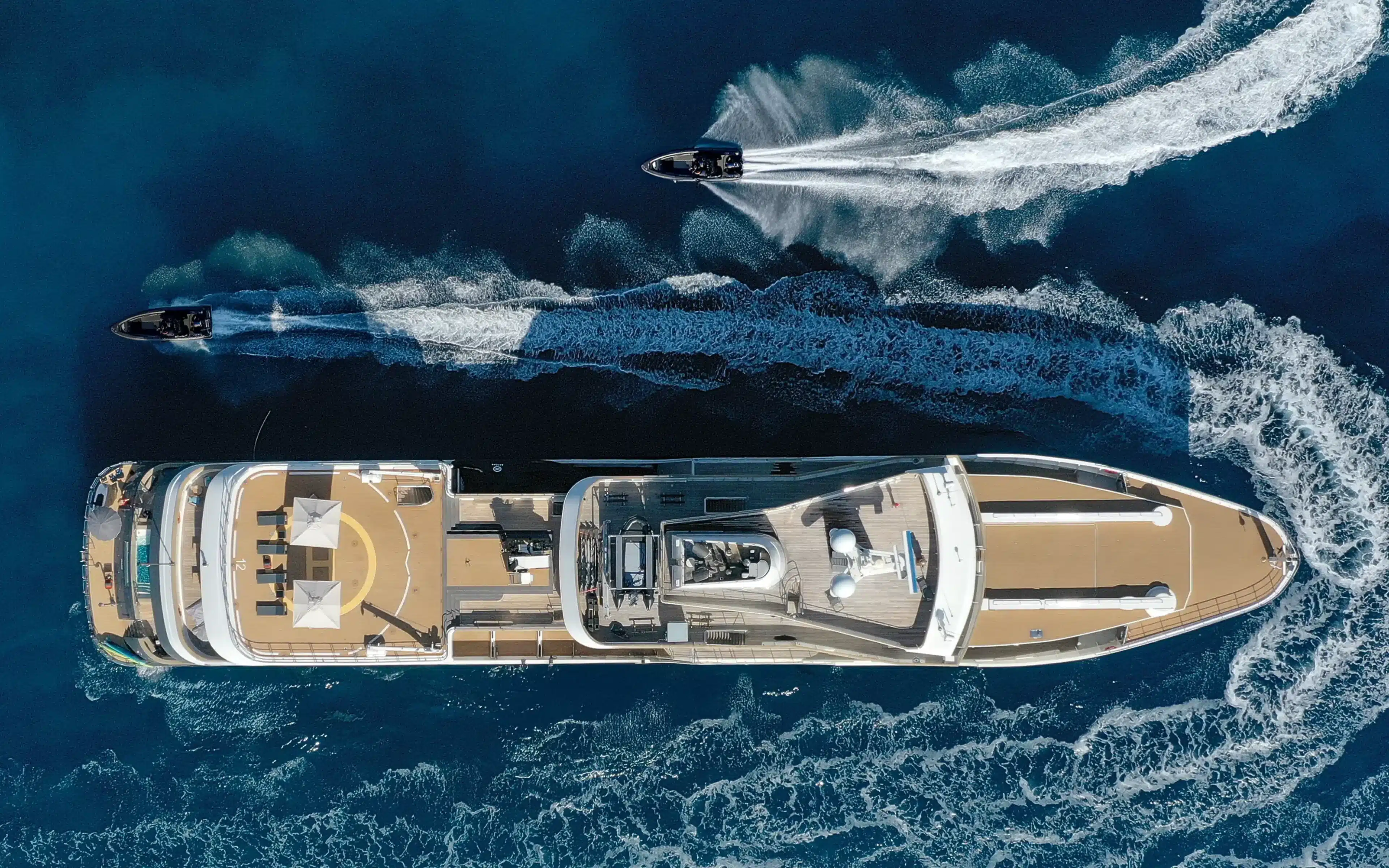 Viewed from above, an Aqua Expeditions vessel is circled by two Zodiacs.