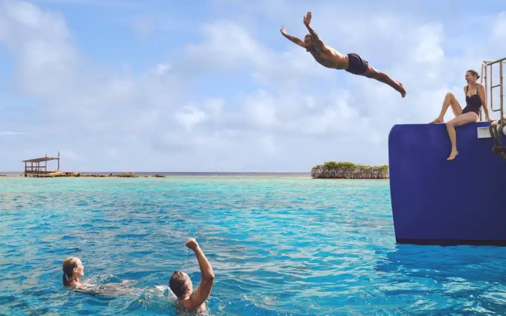 A male dives into the ocean from a floating pontoon.