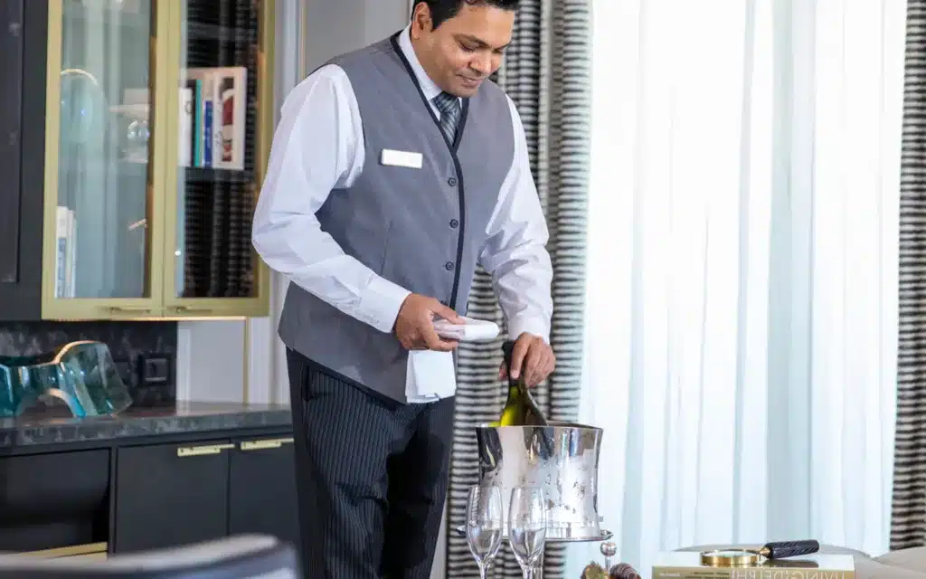 A butler placing champgane in an ice bucket.