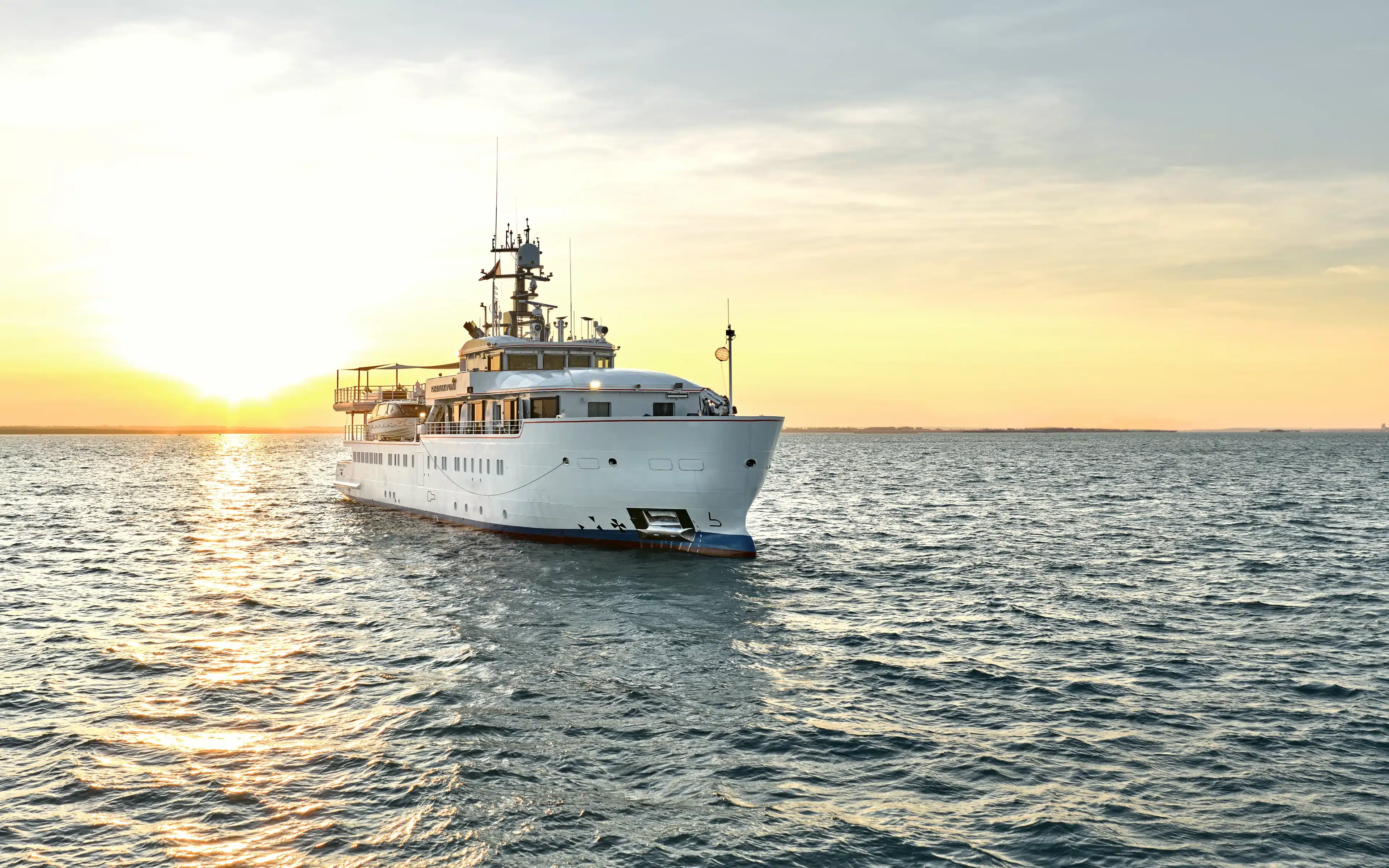 The Paspaley Pearl at sea with the sun setting in the background.