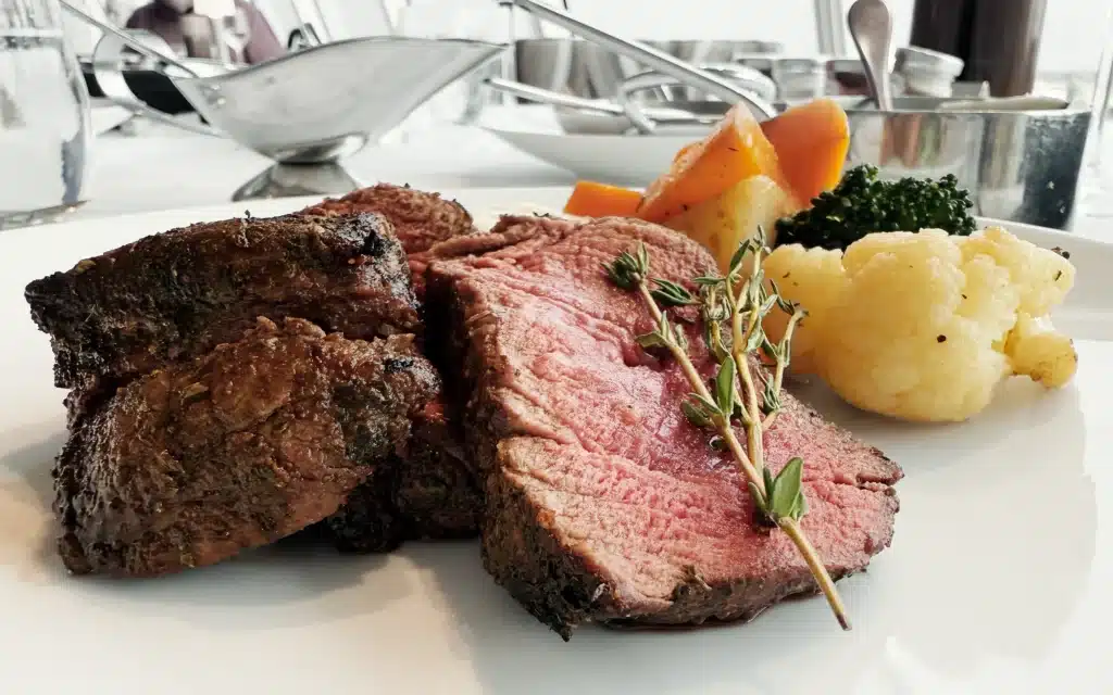 Ruby pink ribeye steak served with vegetables.