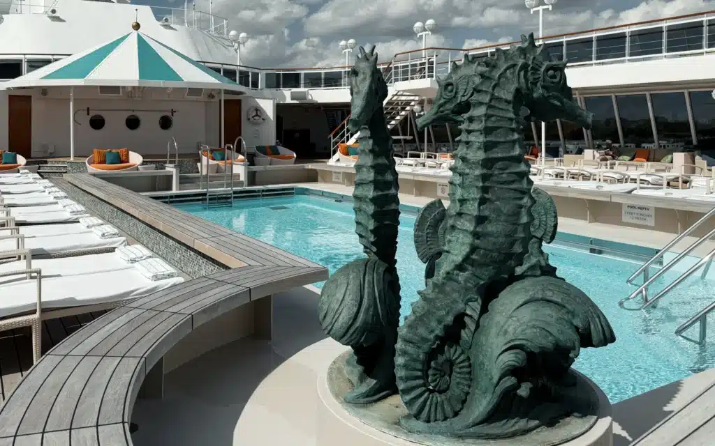 A sculpture of three seahorses on the corner of a swimming pool aboard Crystal Serenity.