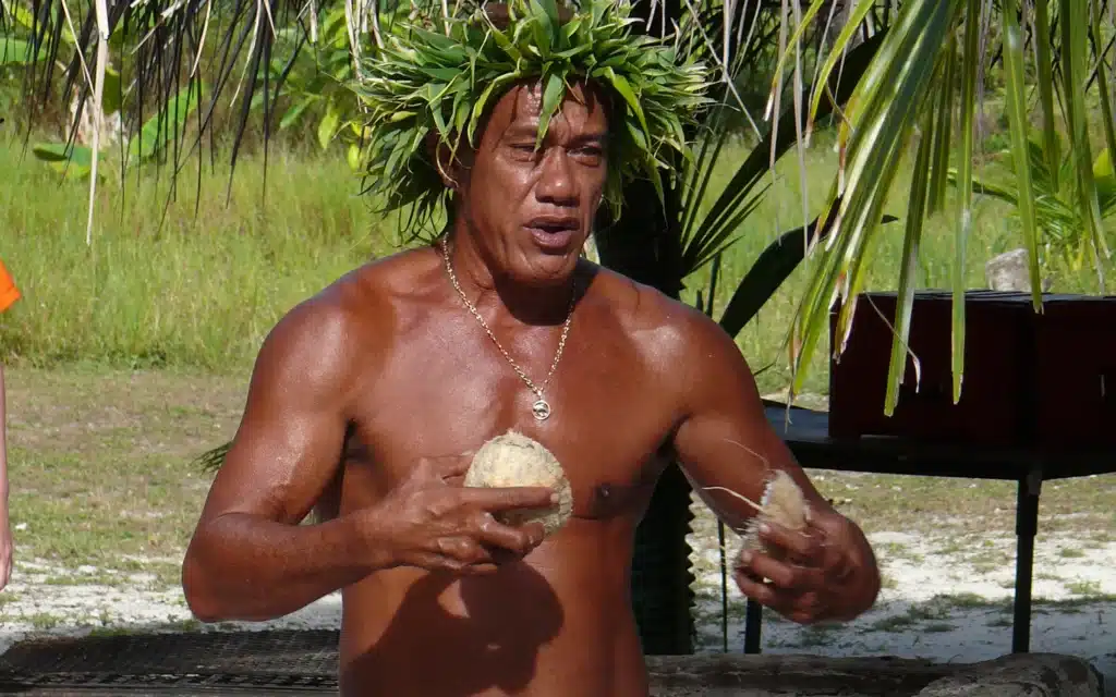 An indigenous French Polynesia demonstrating skills opening coconuts.
