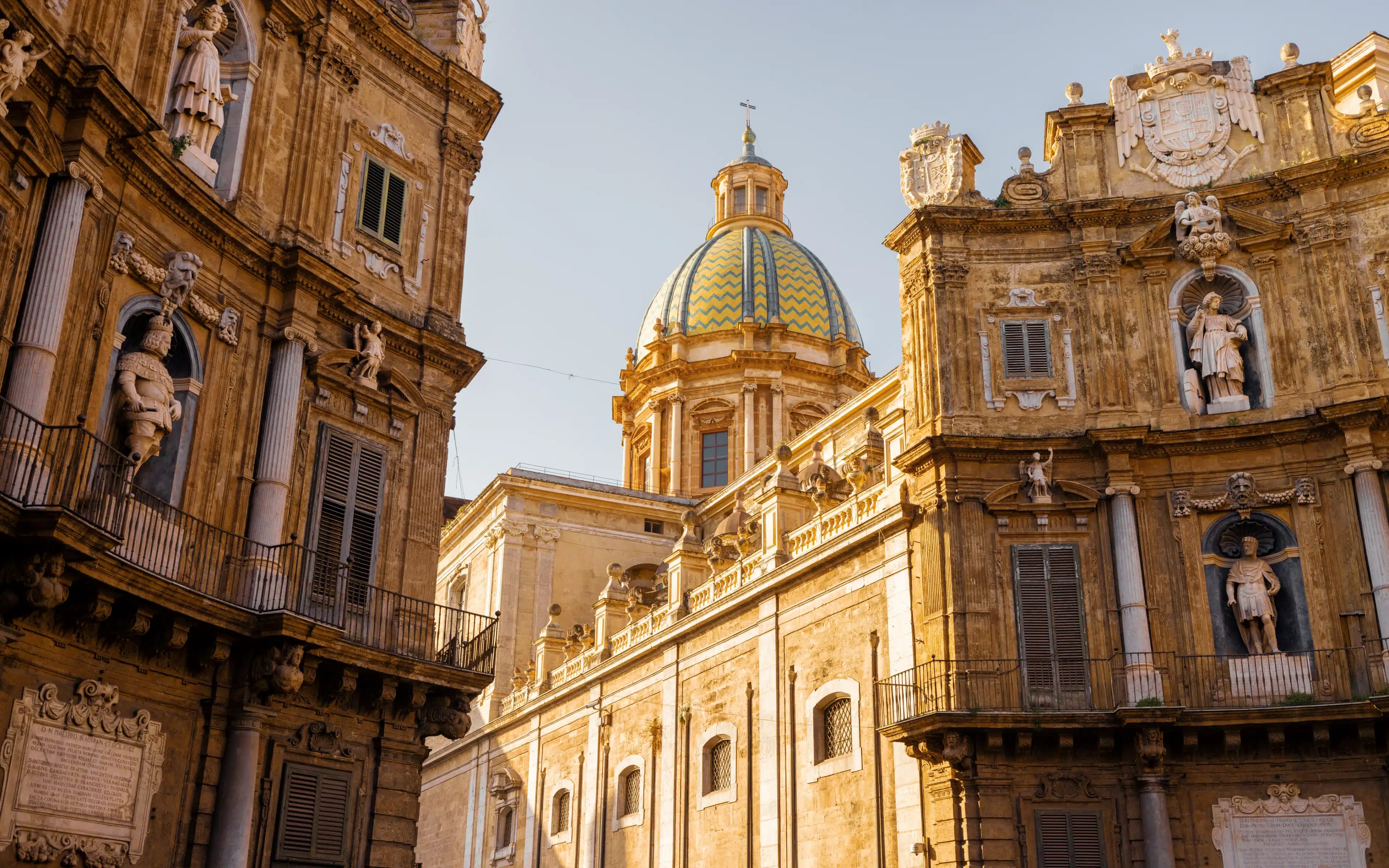 Ornate baroque facades and a blue-and-gold tiled dome at Quattro Canti, Palermo, Sicily