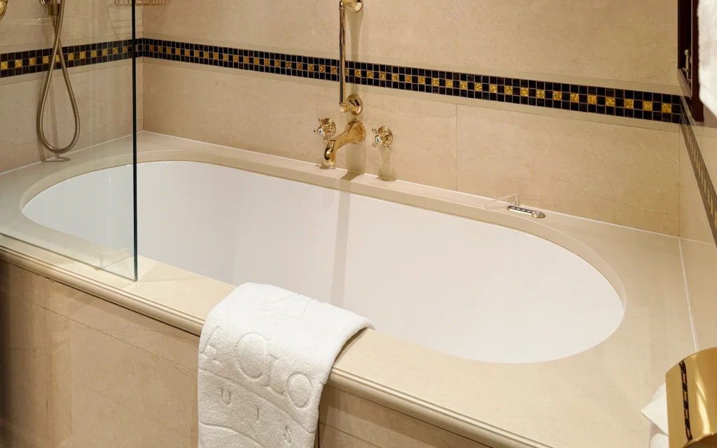 Full-size soaking bath with period-style gold faucets and glass shower screen in the Sea Cloud Spirit Junior Veranda Suite bathroom