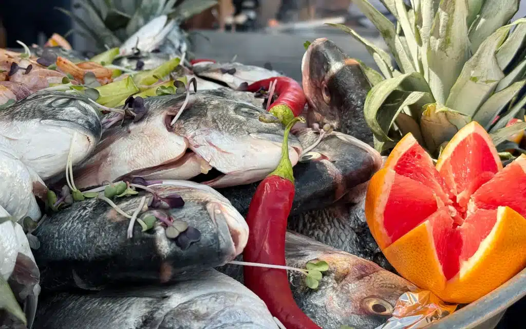 Sea Cloud Spirit deck barbecue raw whole fish display with sea bass, chili, citrus and pineapple garnishes