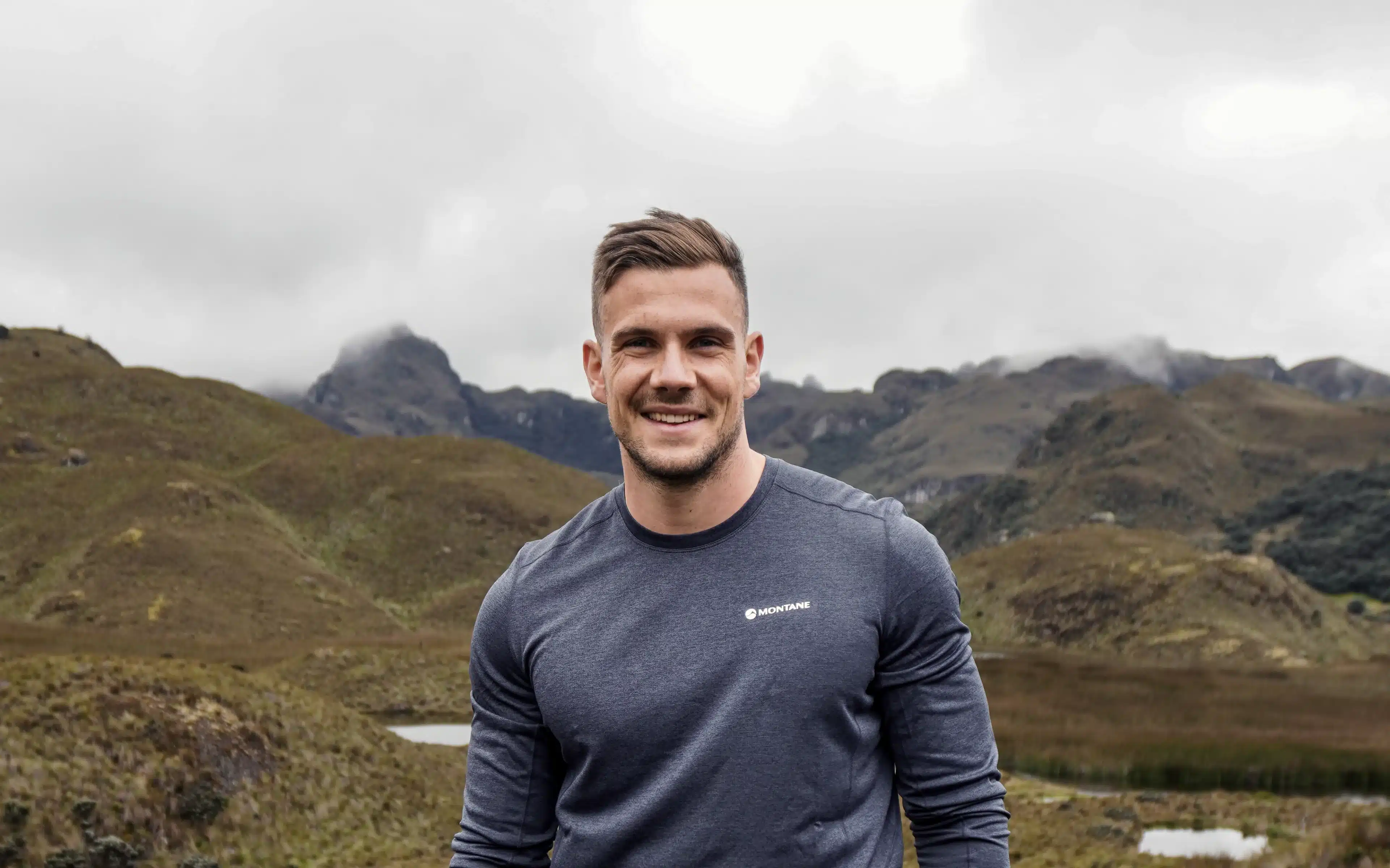 Adam Radcliffe smiling against a backdrop of mist-shrouded highland mountains