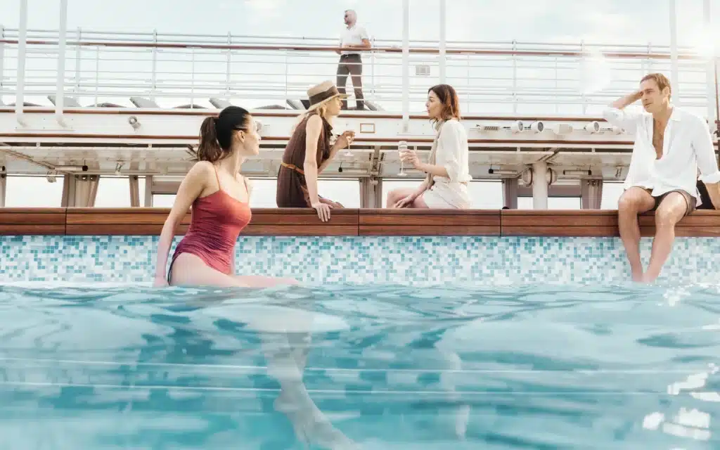 Guests socializing with champagne at the outdoor pool deck aboard a Silversea luxury cruise ship