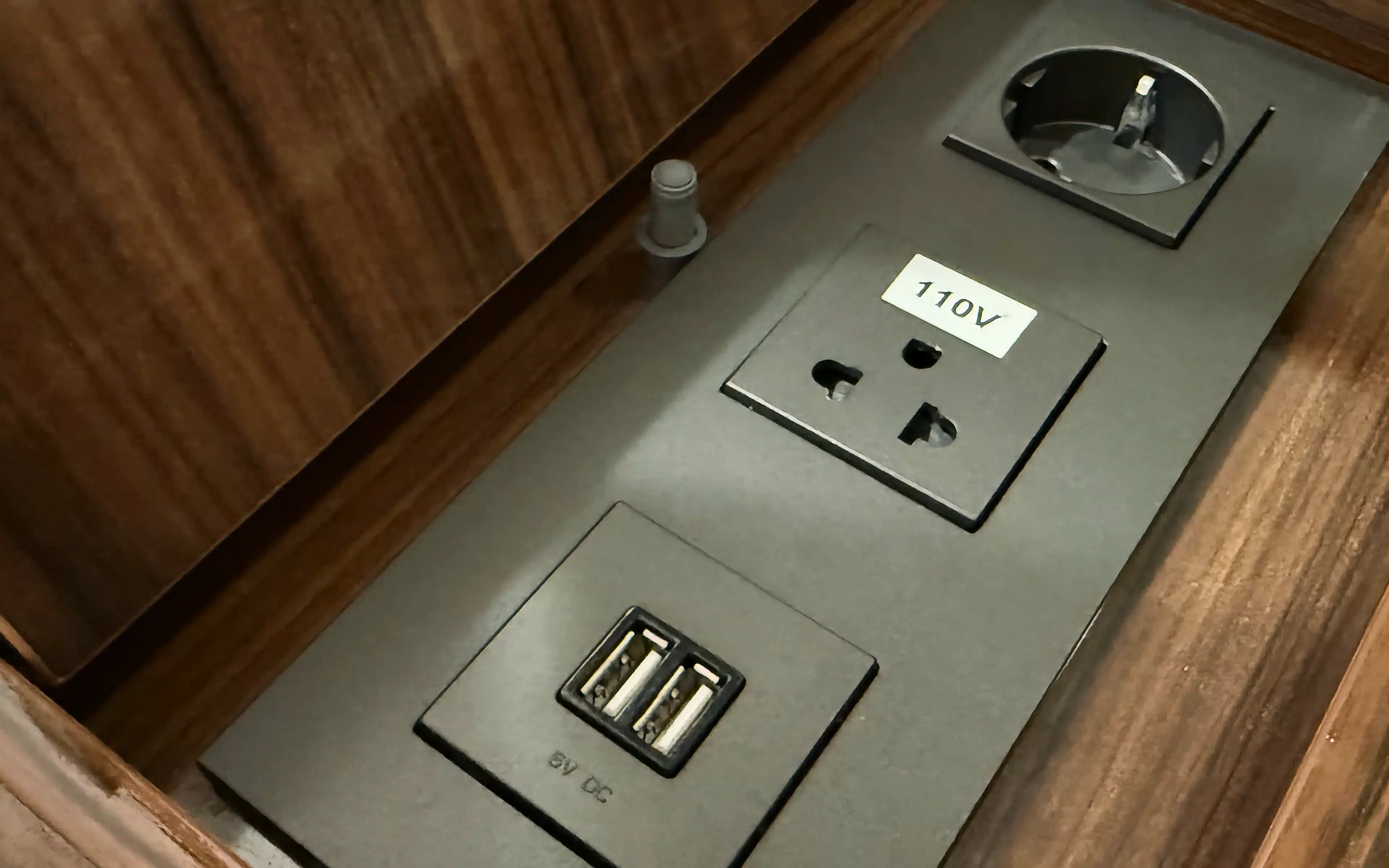 In-suite power outlets in a World Voyager Veranda and Horizon Suite, including a 110V universal socket and dual USB charging ports set into a dark panel