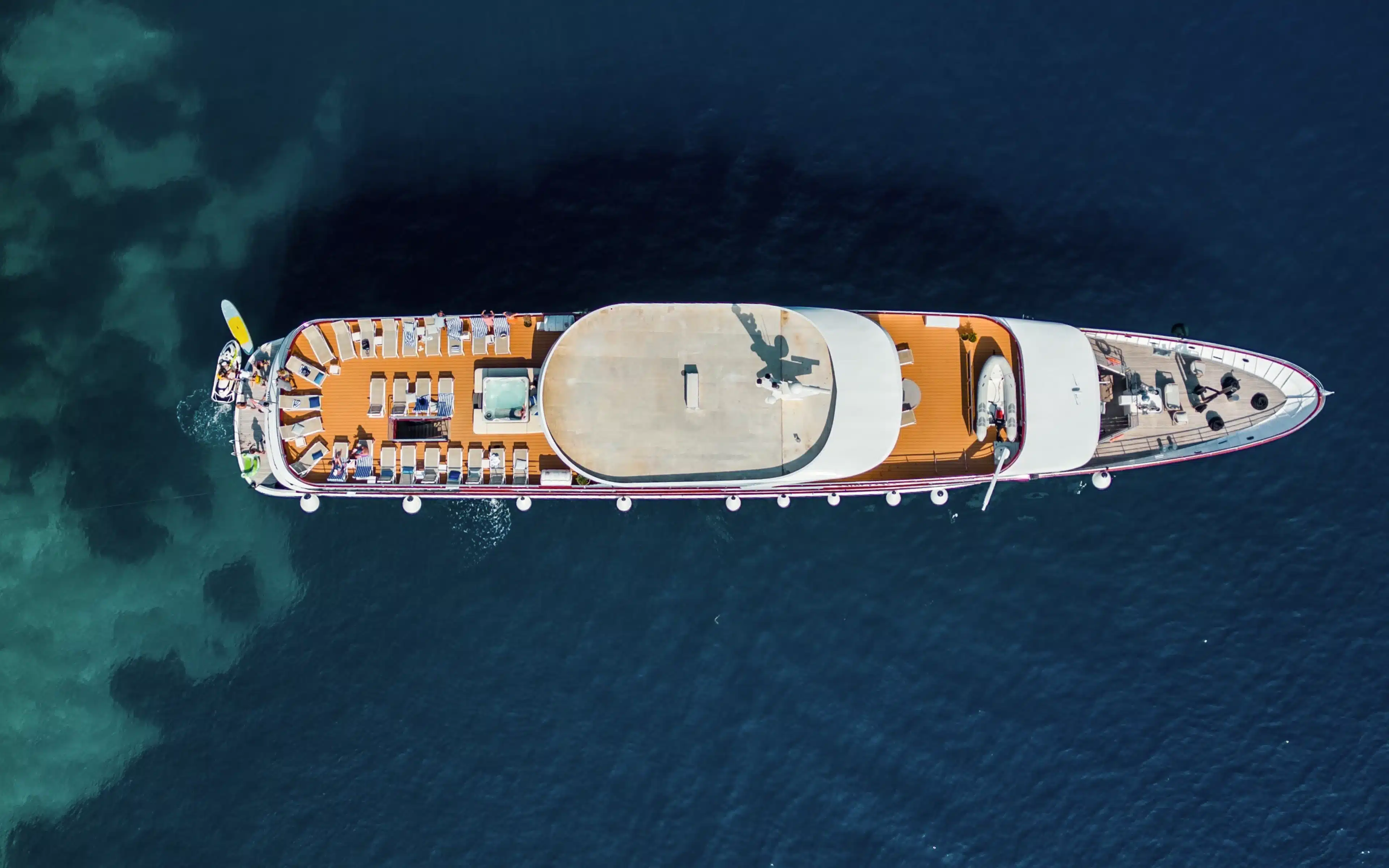 Aerial bird's-eye view of Unforgettable Croatia's ship MV Memories underway, showing the full teak sun deck lined with loungers, a central jacuzzi, and deep blue surrounding waters