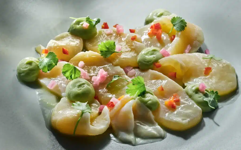 Scallop ceviche plated with avocado and fresh herbs