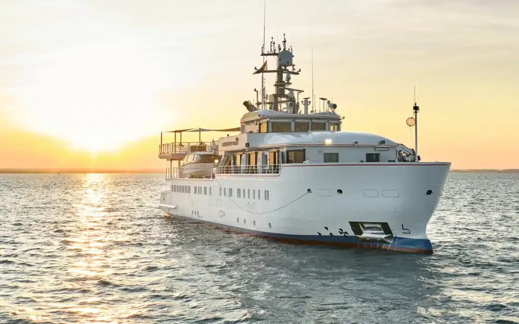 Expedition yacht cruising at sunset with tender aboard