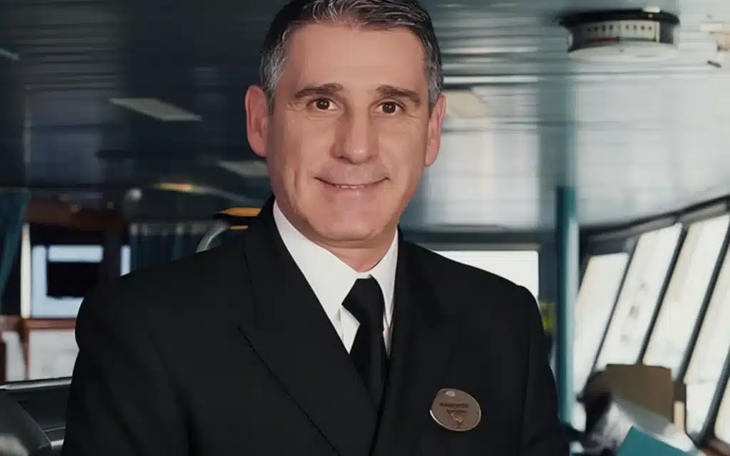 Ship's captain in dark uniform smiling on the bridge