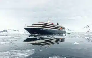 World Navigator cruise ship reflected in still Antarctic waters surrounded by ice floes