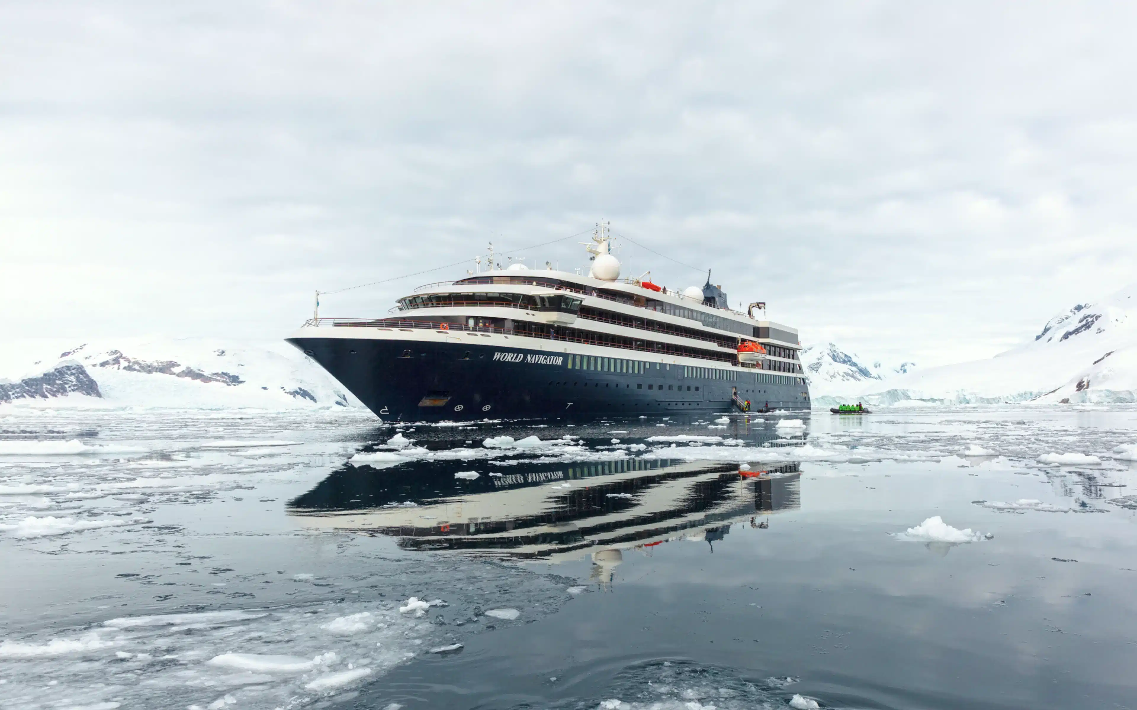 World Navigator cruise ship reflected in still Antarctic waters surrounded by ice floes