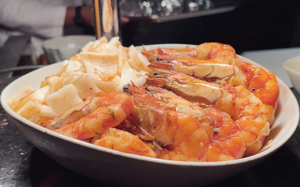 Grilled whole prawns served alongside sliced daikon radish