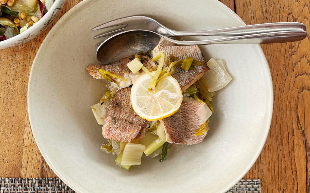 Pan-seared red snapper with celery and lemon on white plate