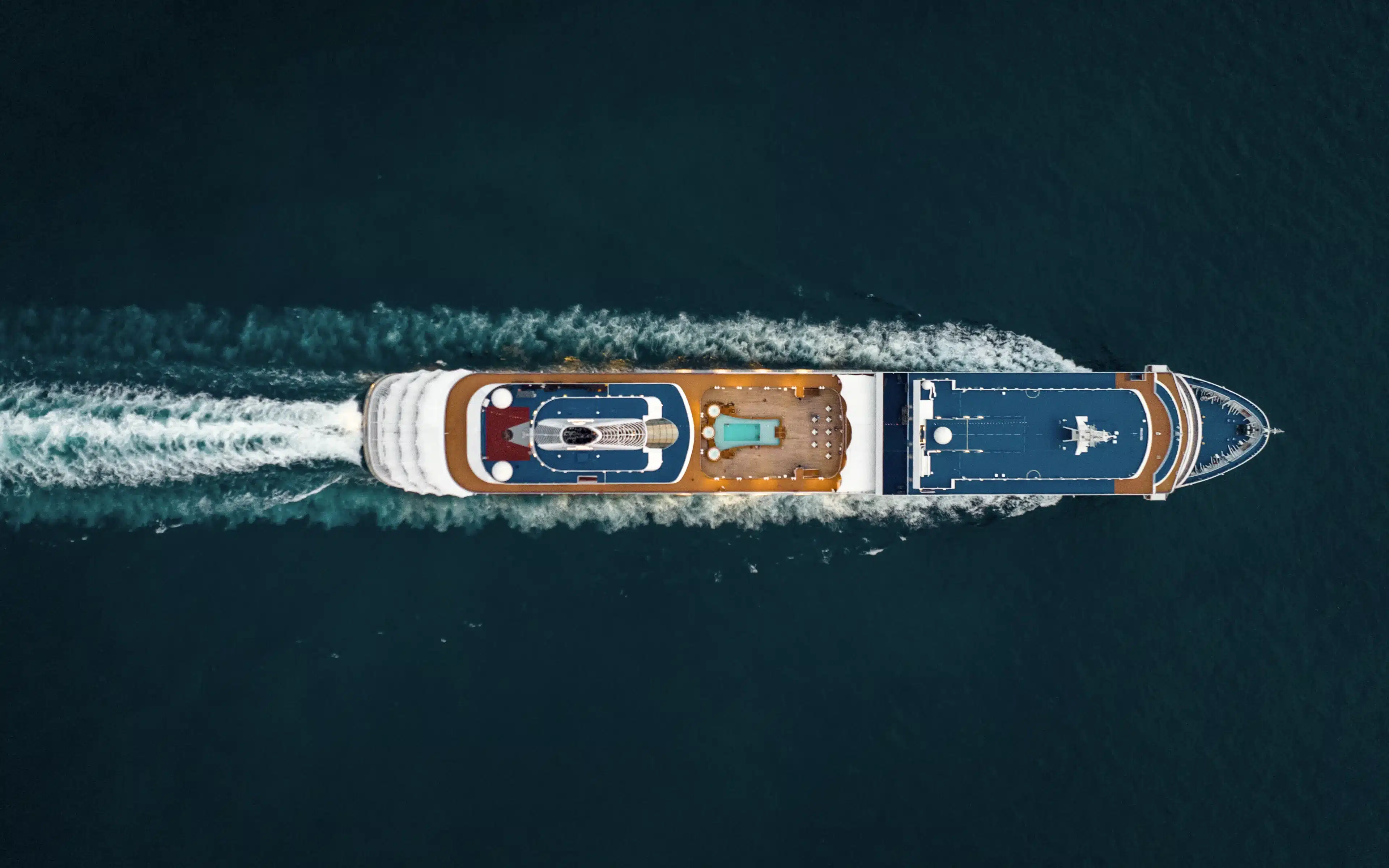 Aerial view of a Silversea cruise ship carving a wake through dark blue ocean