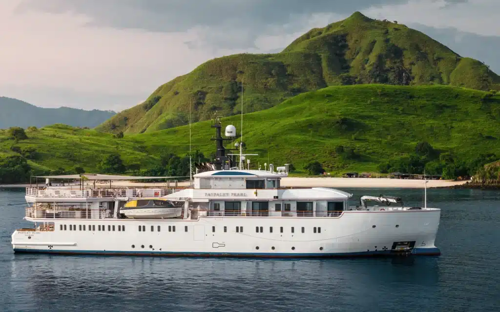 Paspaley Pearl expedition yacht anchored beside a forested island headland