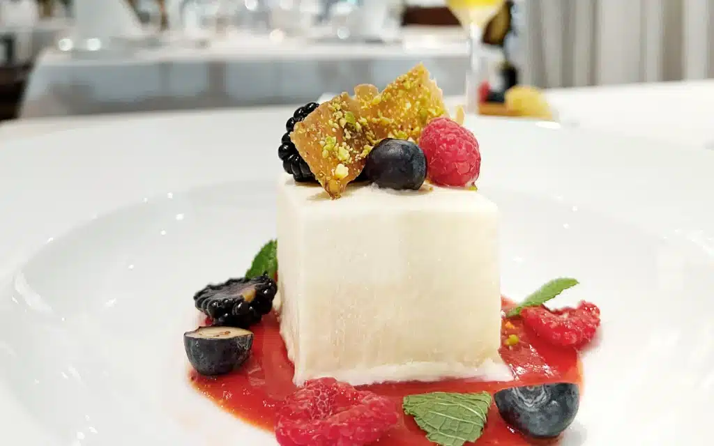 White panna cotta topped with berries and pistachio tuile