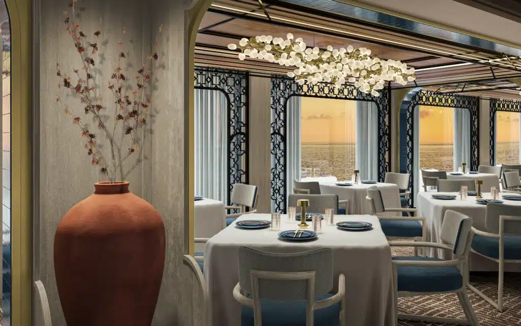 Elegant restaurant interior with a gold branch chandelier, terracotta vase and ocean views at sunset