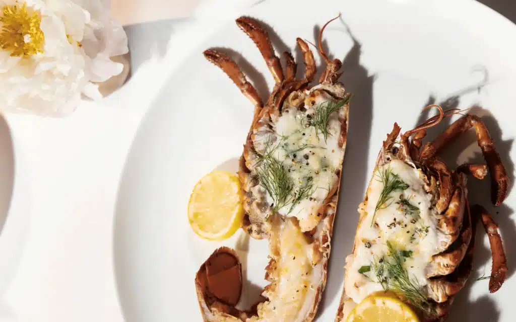 Grilled lobster tail halves topped with herb butter and cracked pepper, served with lemon slices