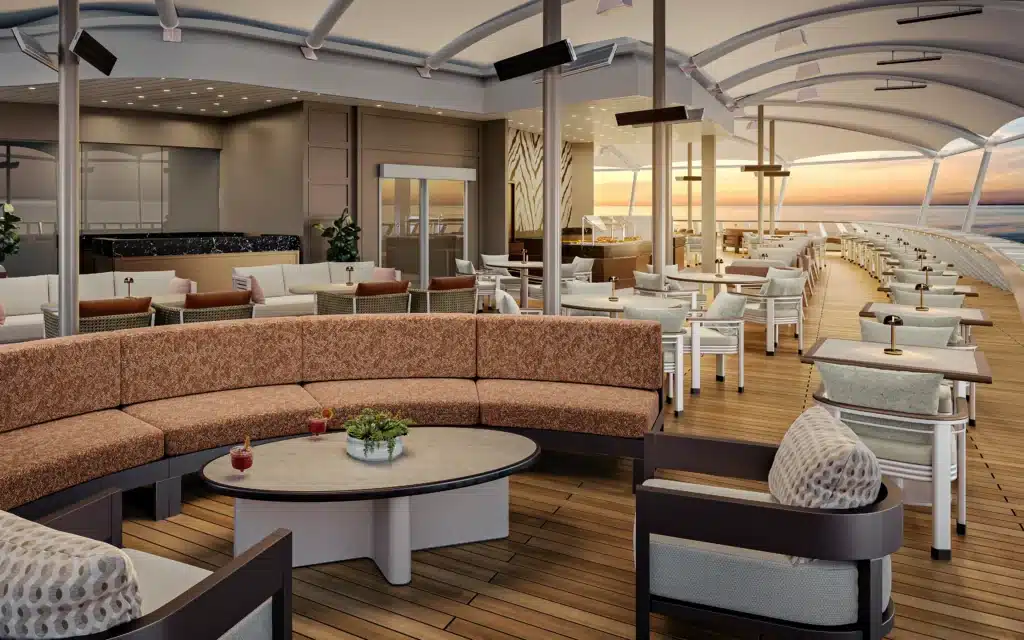 Open-air terrace lounge with sofas and teak decking overlooking the ocean at sunset