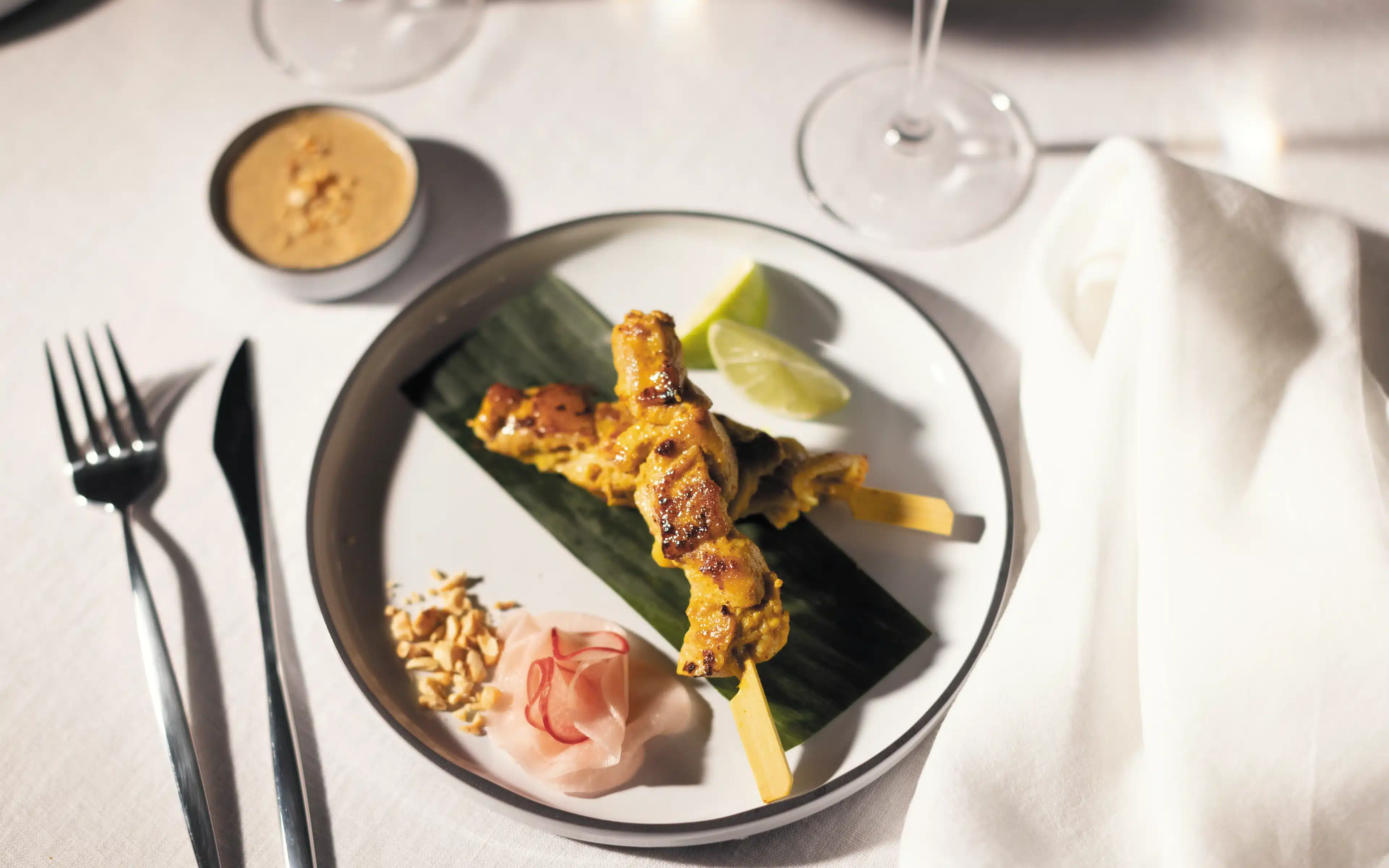 Chicken satay skewer with peanut sauce, crushed peanuts and lime wedges