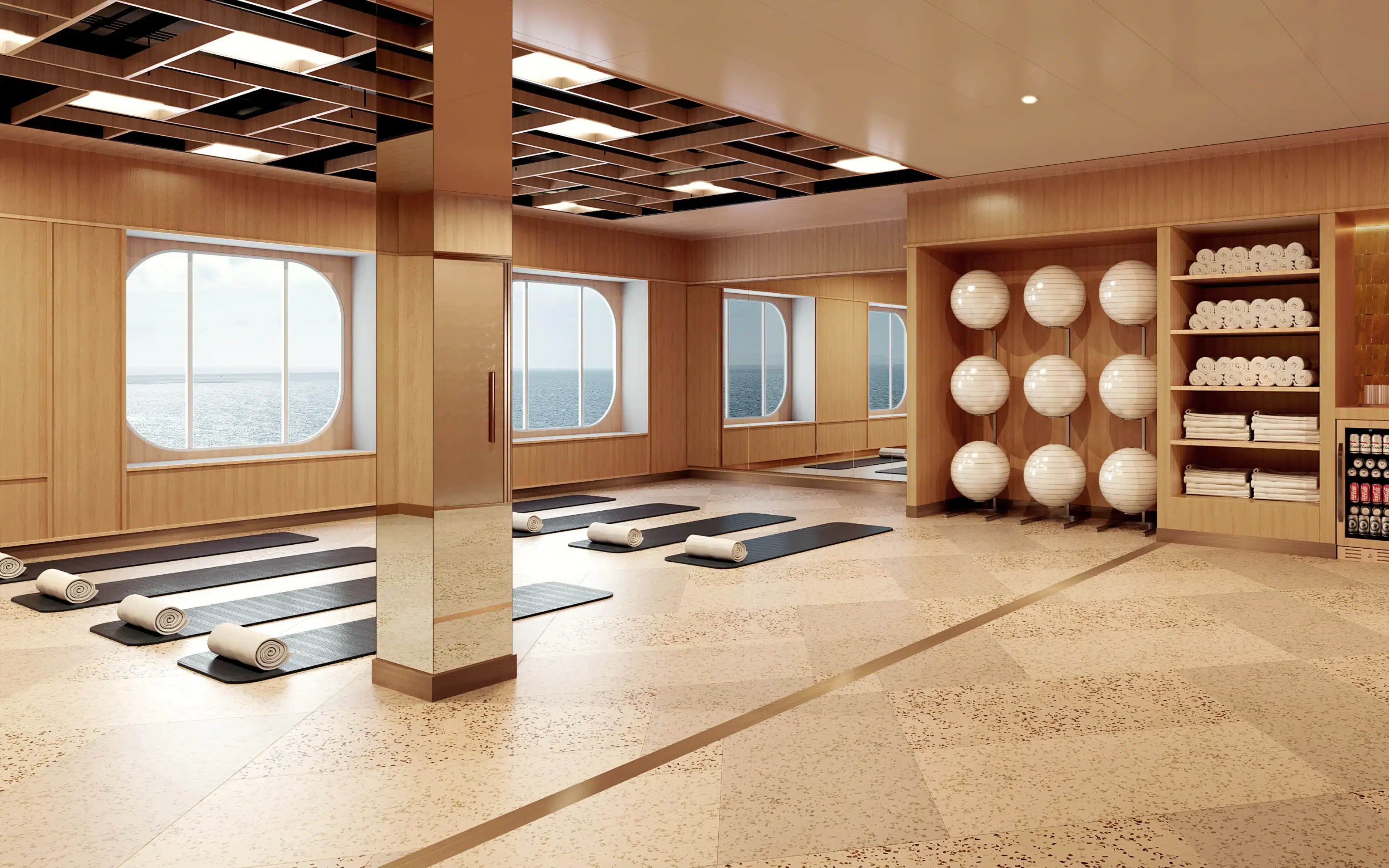 Yoga mats and rolled towels wait beside ocean-view windows