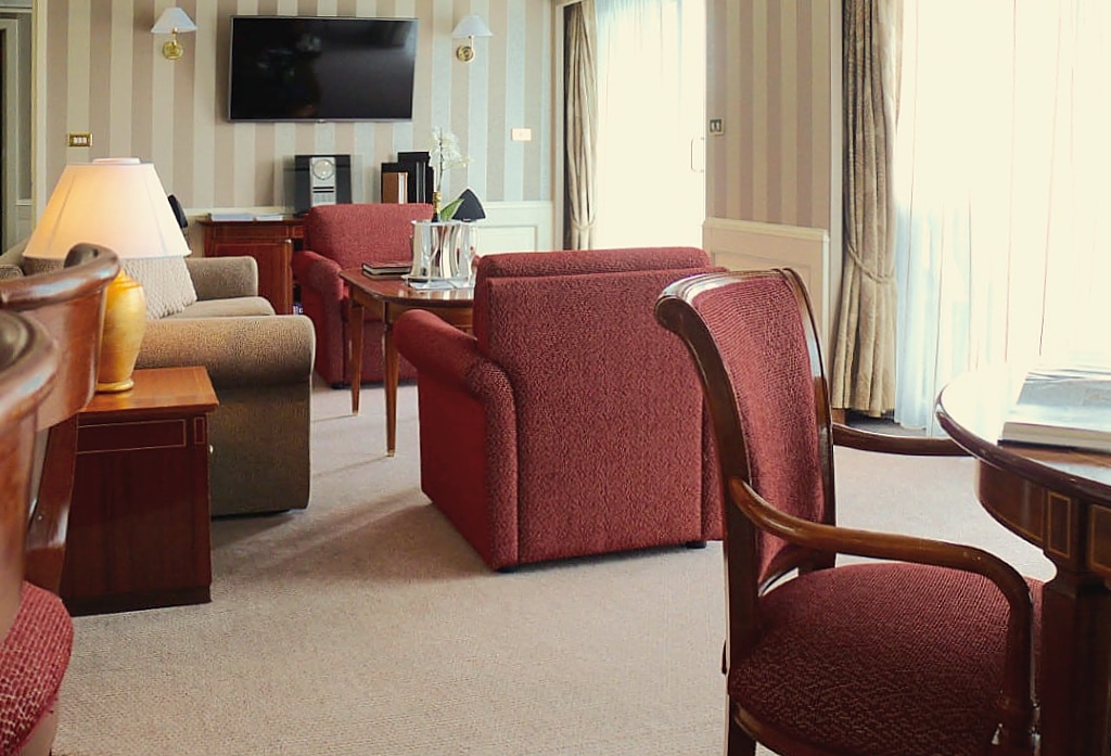 Owner's Suite living area aboard Silversea's Silver Whisper with striped walls and burgundy armchairs