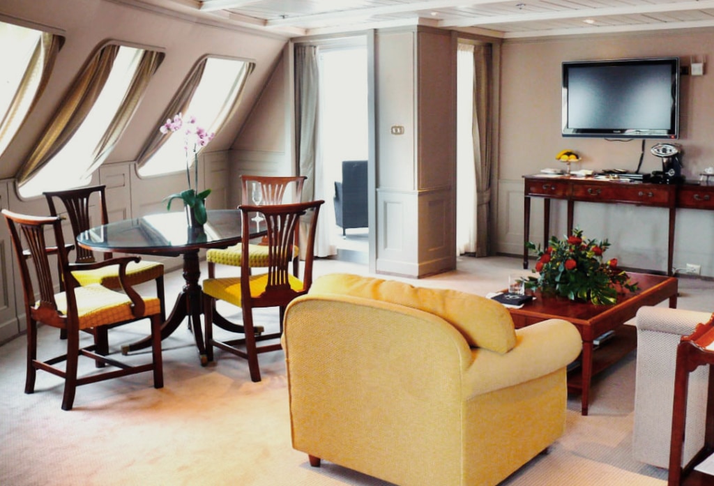 Grand Suite living and dining area aboard Silversea's Silver Wind with wood paneling and yellow armchairs